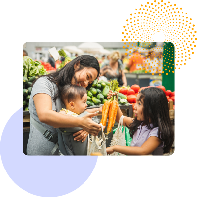 A mother and her children shopping and buying carrots at a grocery store