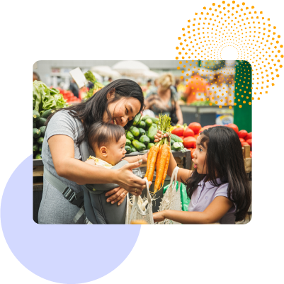 A mother and her children shopping and buying carrots at a grocery store