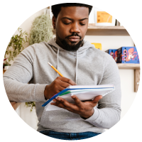 a multi-racial man listing down his expenses on a notebook using a pencil