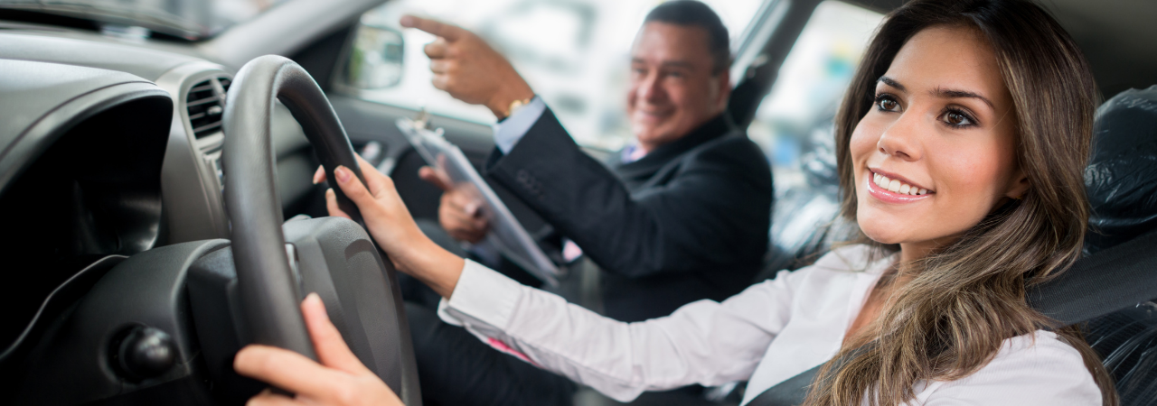 a woman test driving a new car with a salesman pointing out the latest features